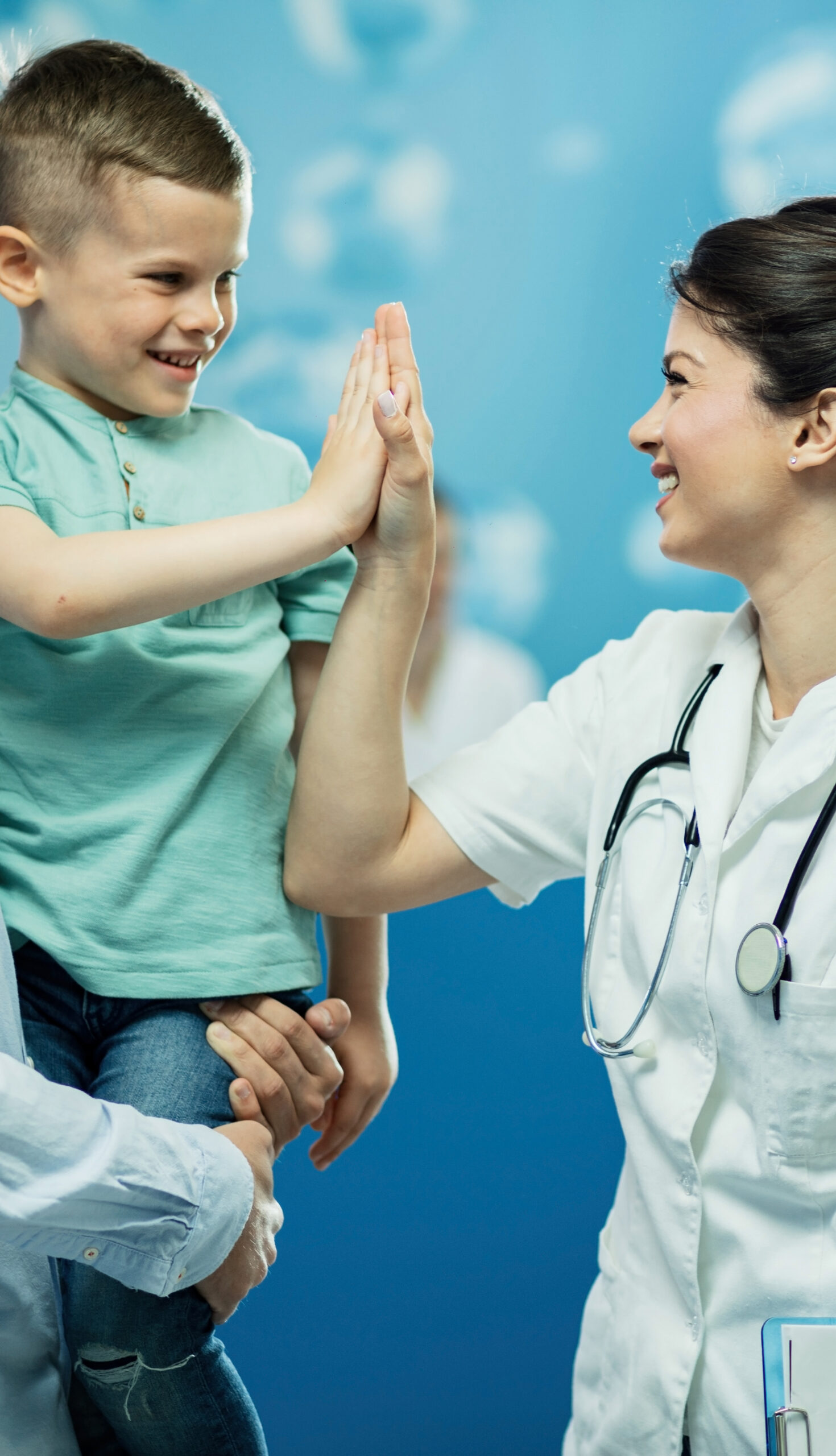 Happy female doctor giving high fie to a little boy who came with father at hospital.